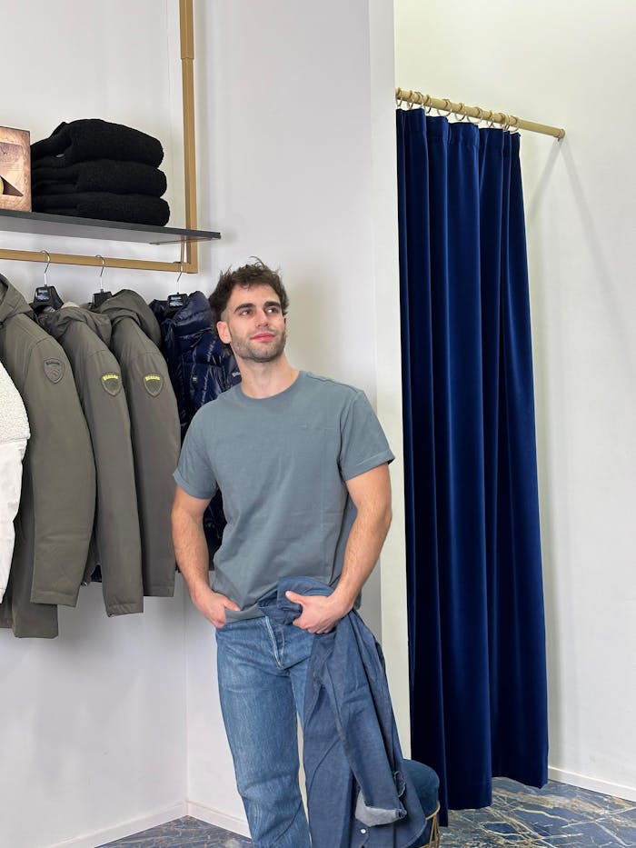 Man in casual outfit poses in a modern clothing store with winter jackets.